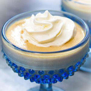 Closeup of a blue dessert dish with high protein banana pudding with whipped cream.