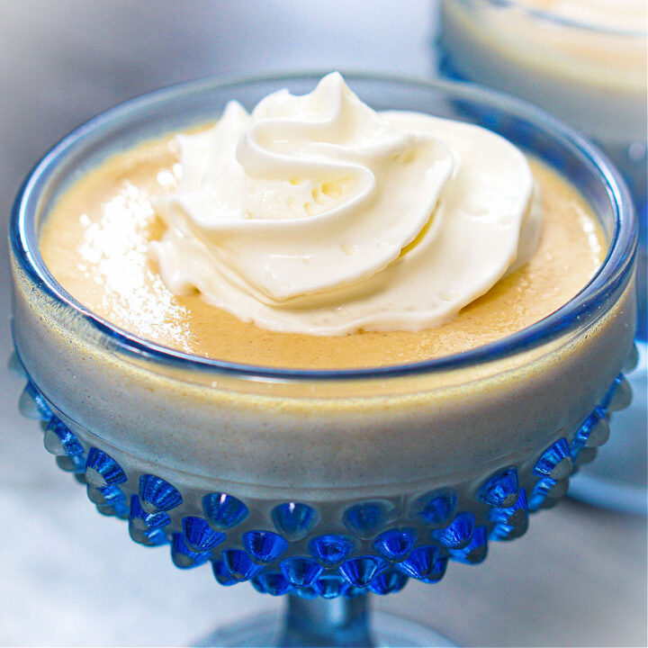 Closeup of a blue dessert dish with high protein banana pudding with whipped cream.