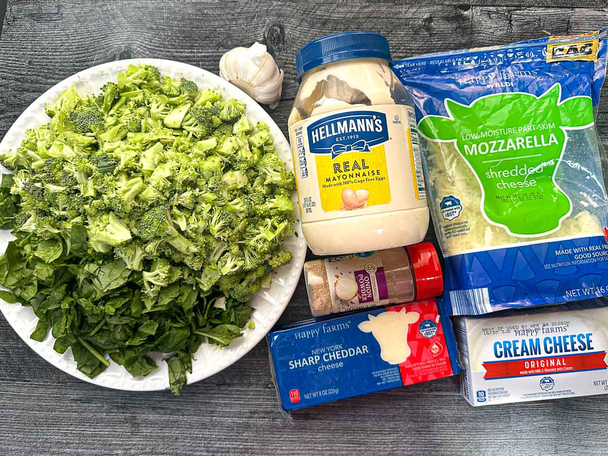 Recipe ingredients - chopped broccoli, baby spinach, mayo, garlic, cheddar, onion powder, creamy cheese and mozzarella.