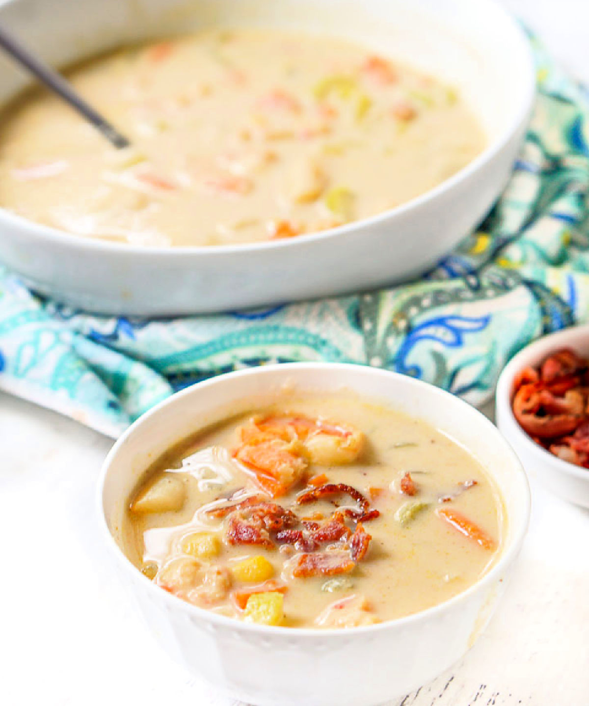 A serving of the low carb seafood chowder and a large bowl of it in the background.