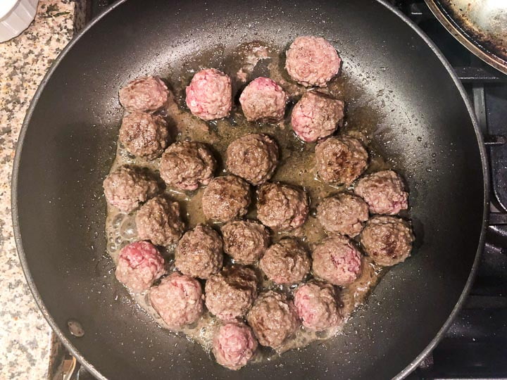 skillet on the stove with meatball browning