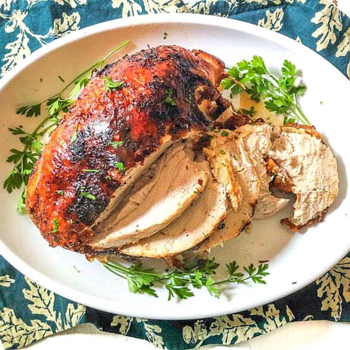 white platter with roasted air fryer turkey breast with sprigs of parsley