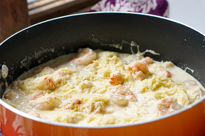closeup of an orange pan with creamy gluten free pasta with shrimp and scallops