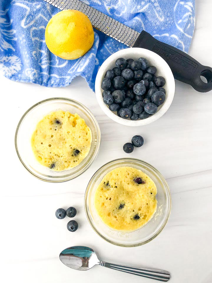 two glass dishes with 1 minute blueberry muffins and a bowl of blueberries, lemon and microplane