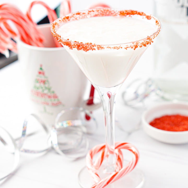 martini glass with keto candy cane drink with a mug full of candy canes in the background