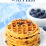 closeup of a white plate with a stack of keto blueberry waffles and fresh blueberries in background and text