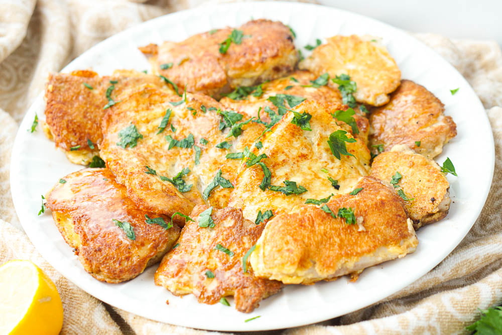 a white platter of keto tilapia Romano with parsley on top