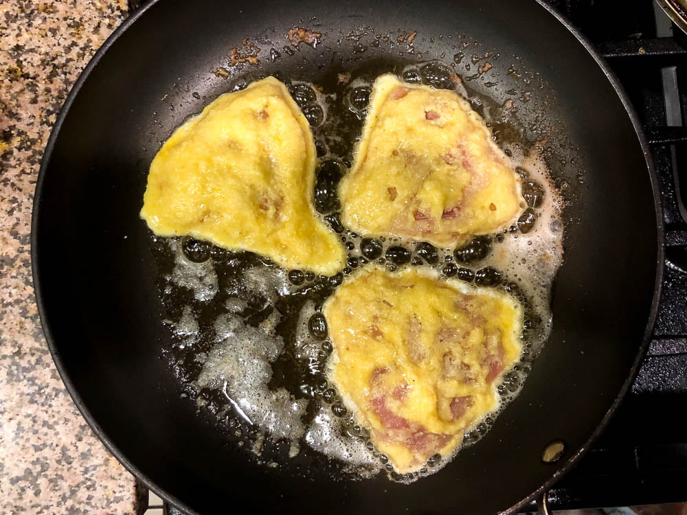 black skillet with 3 pieces of low carb tilapia Romano sizzling