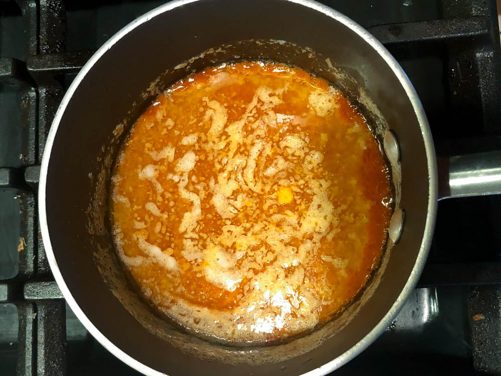 A saucepan on the stove with low carb buffalo sauce