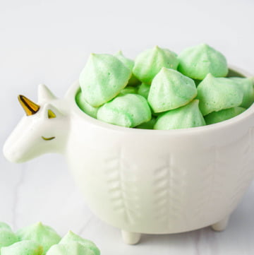 white unicorn bowl filled with green keto meringue cookies