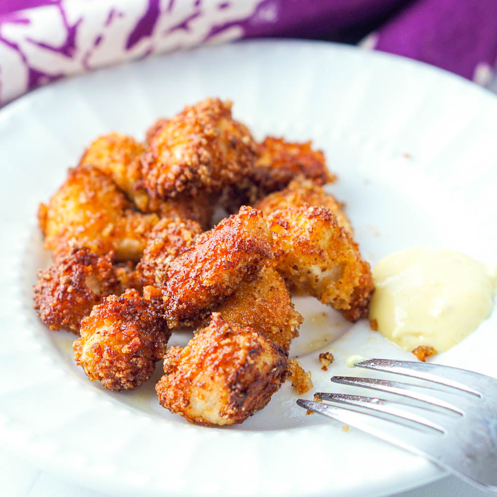 closeup of keto popcorn chicken made in the air fryer on a white plate with a fork