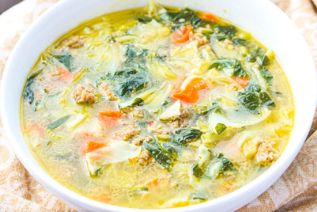 Closeup of a white bowl of the low carb veggie and sausage soup.