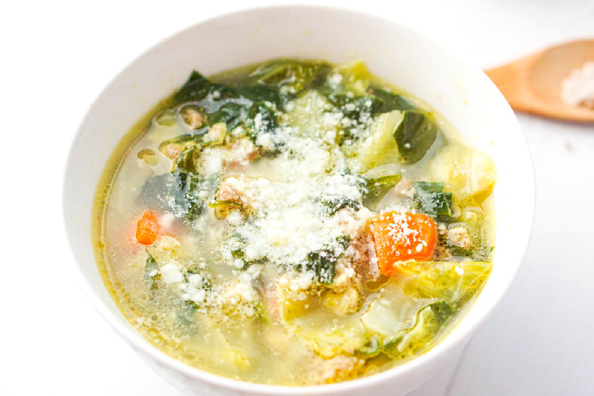 Closeup of the finished soup in a white bowl with parmesan cheese on top.
