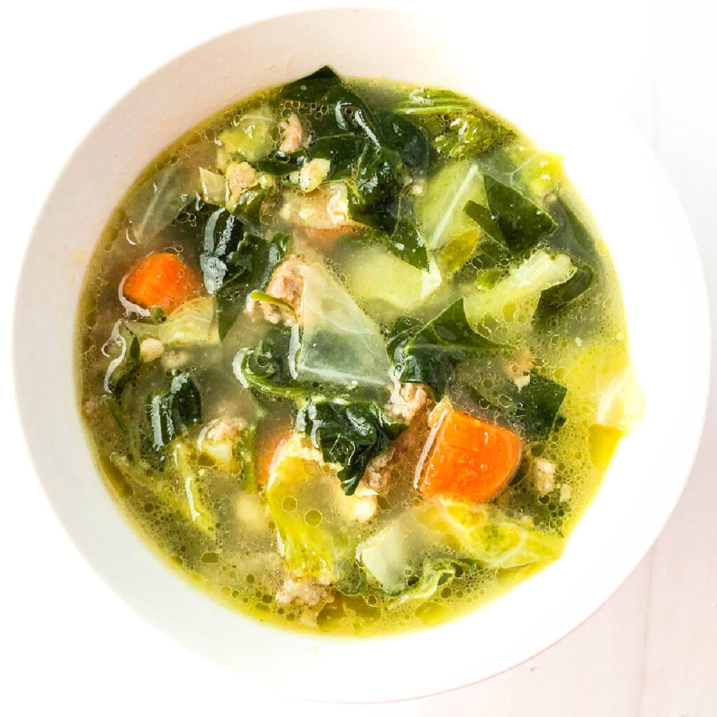 Aerial view of a white bowl of keto sausage cabbage soup.