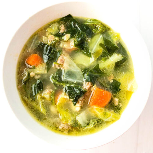 Aerial view of a white bowl of keto sausage cabbage soup.