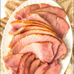 white platter with sliced apricot bourbon glazed ham and text overlay
