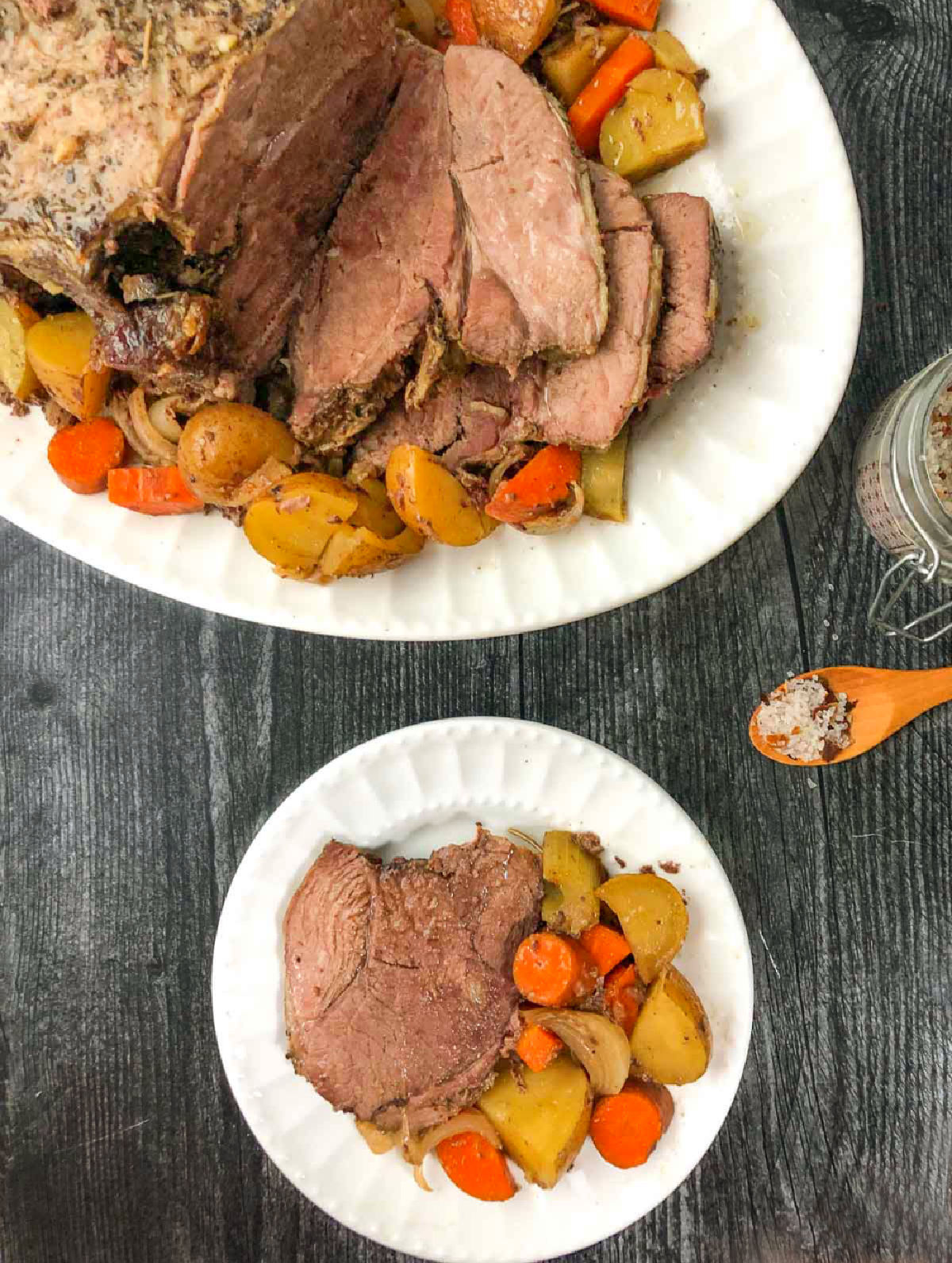 aerial view of a white platter with crock pot lamb roast and a plate with a serving