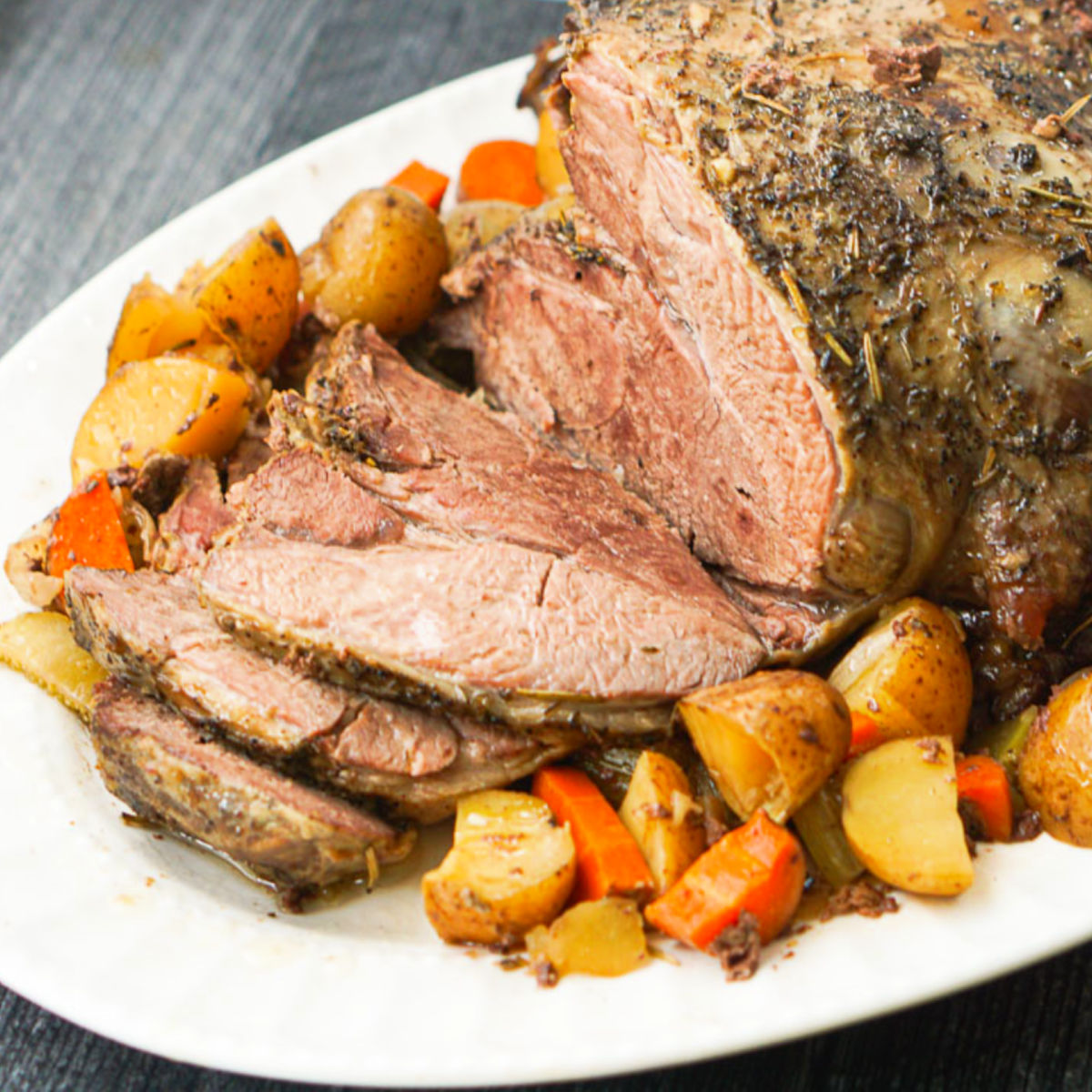 closeup of crock pot lamb roast with roasted veggies on a platter