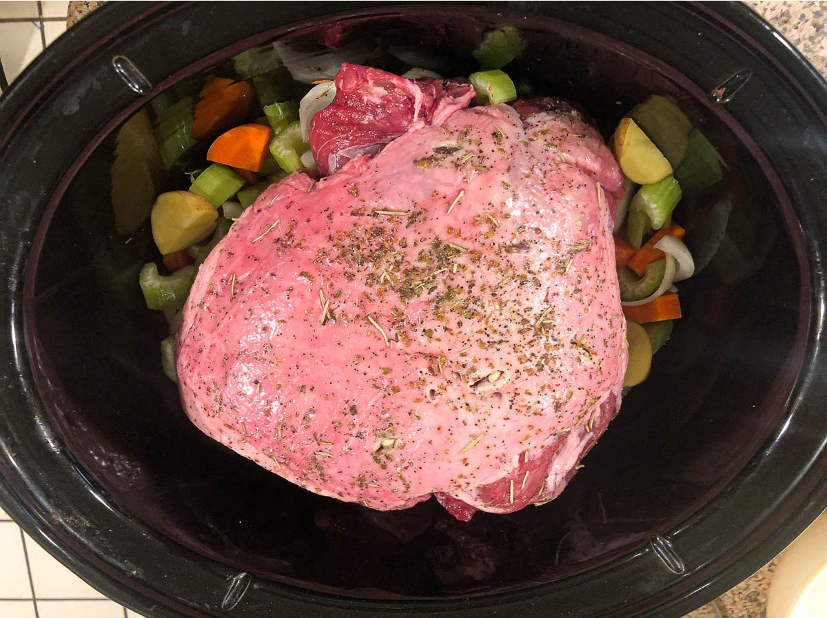 slow cooker with the raw lamb and veggies ready to cook