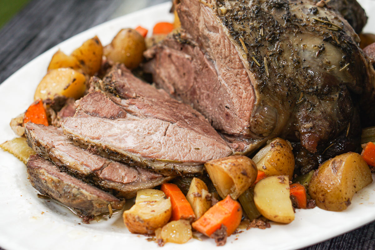closeup of a slow cooker lamb roast sliced with roasted vegetables