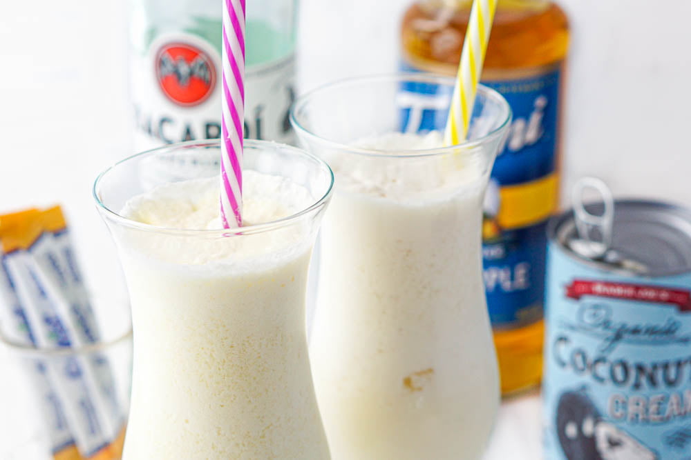 two glasses of frozen pina coladas with keto ingredients in the background