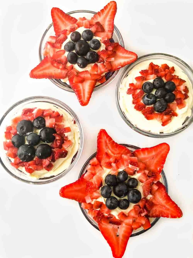 aerial view of 4 dessert dishes with keto jello desserts decorated with strawberries and blueberries