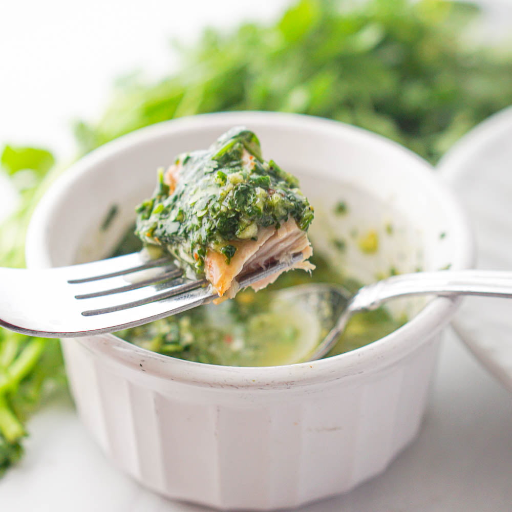 small white ramekin with cilantro chimichurri sauce and a fork with a piece of tuna