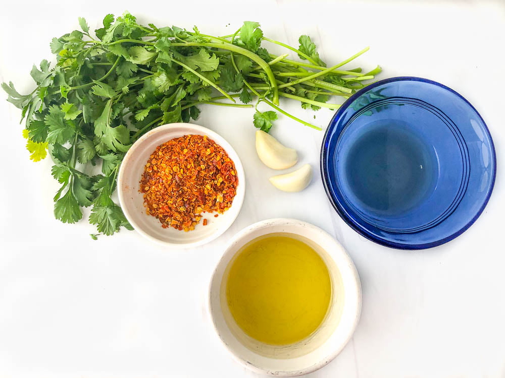 ingredients to make chimichurri - cilantro leaves, garlic, vinegar, olive oil and red pepper flakes