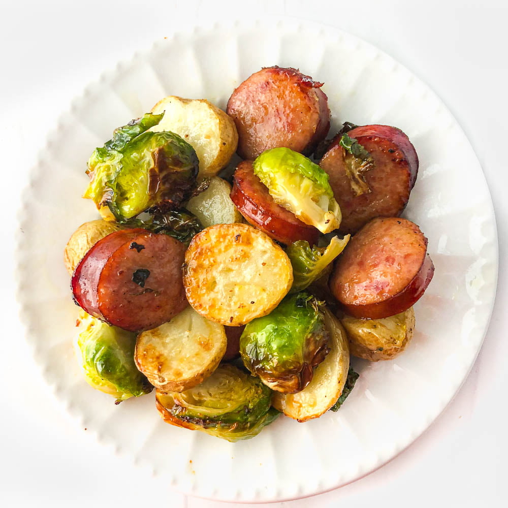 white plate with potatoes, Brussels and kielbasa made in the air fryer