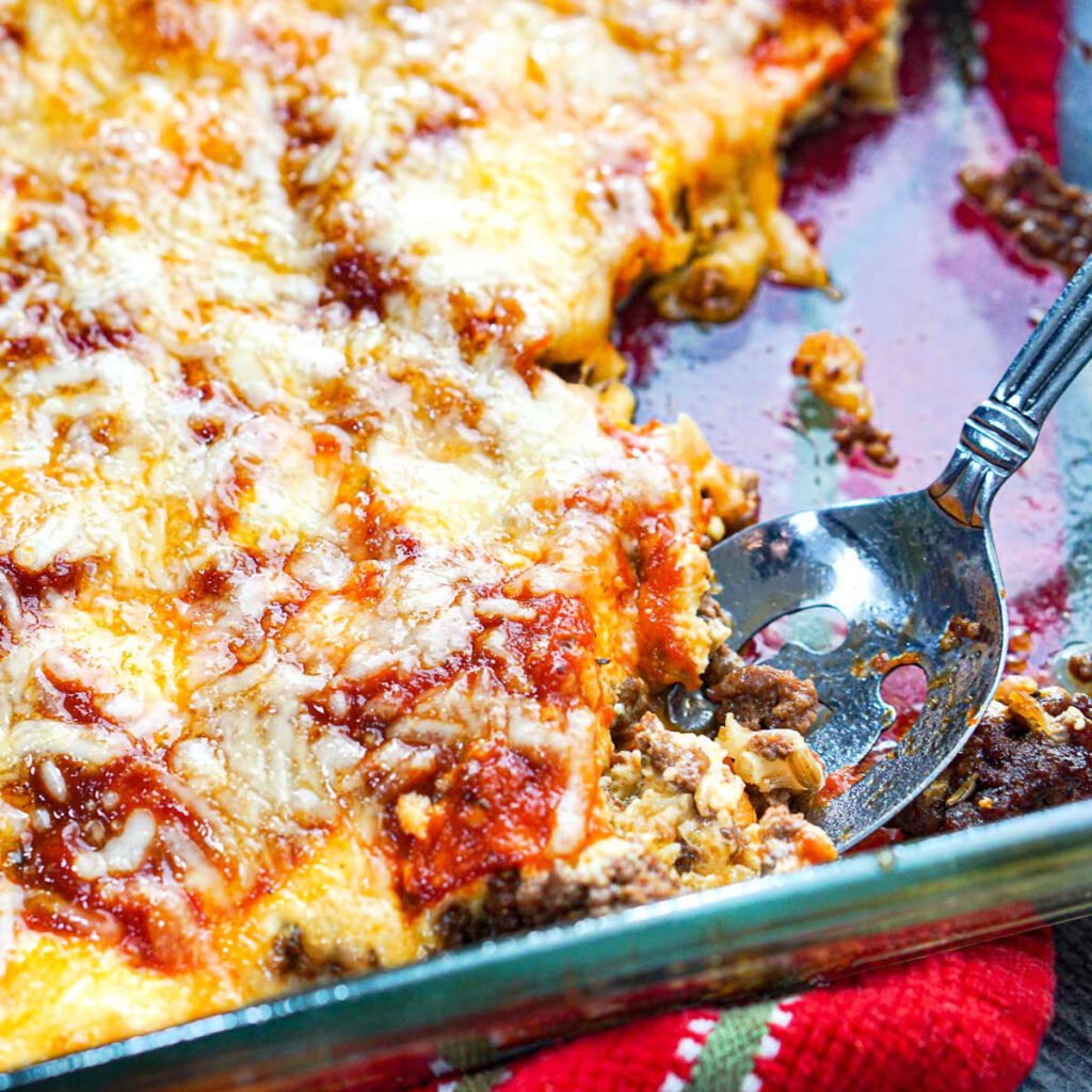 Baking dish with a spoon with the keto ground beef casserole.