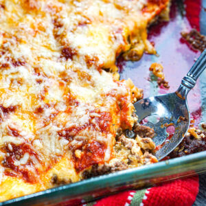 Baking dish with a spoon with the keto ground beef casserole.
