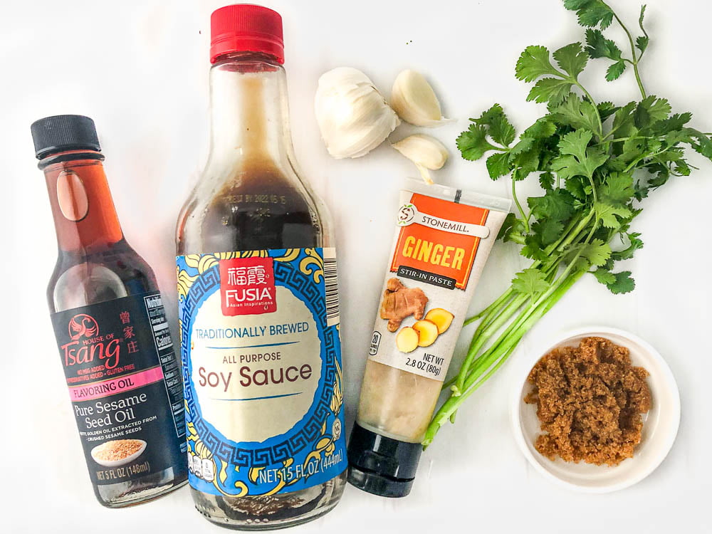 ingredients for salad dressing - sesame oil, soy sauce, garlic, ginger, cilantro and Swerve brown sugar