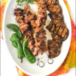 white platter with grilled pork kebabs and text