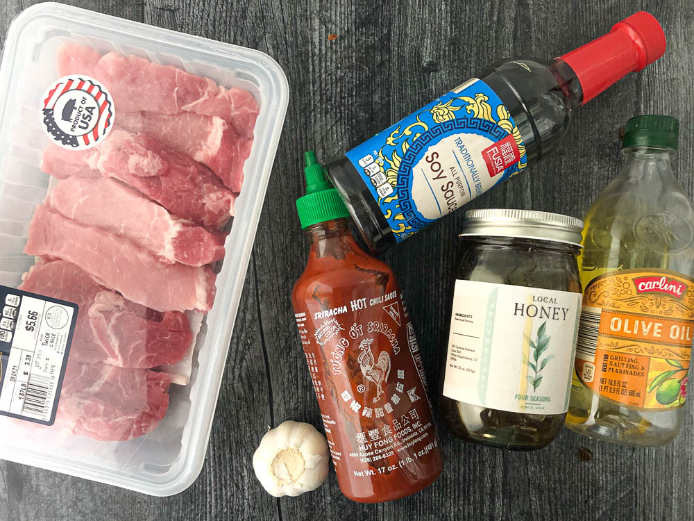 ingredients for pork marinade- country pork ribs, soy sauce, sriracha sauce, garlic cloves, honey and olive oil 