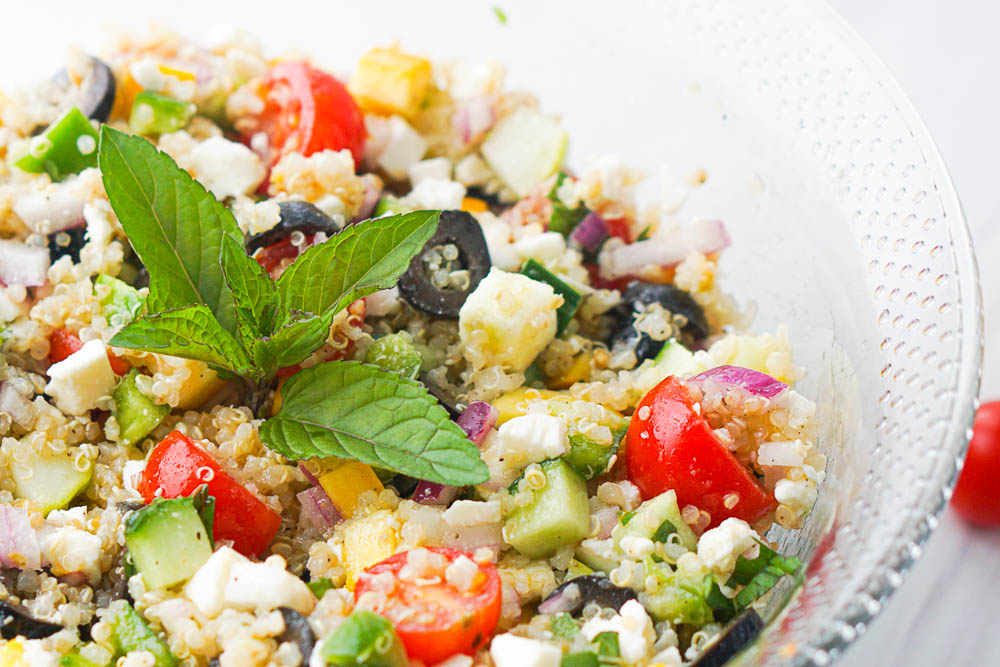 closeup of healthy salad with quinoa and a sprig of mint in the middle