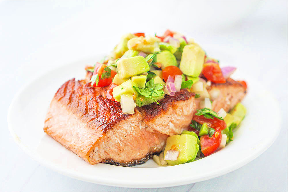 closeup of a piece of salmon topped with fresh avocado salsa