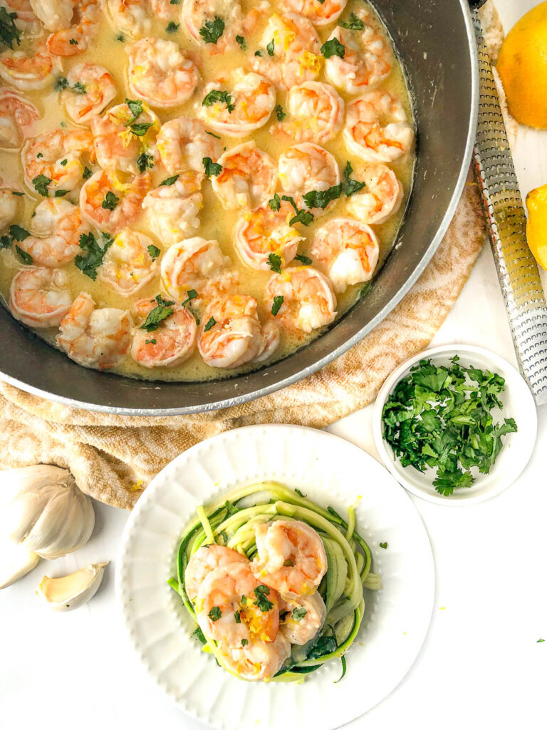 pan and plate with garlic butter shrimp and zucchini noodles with parsley and garlic