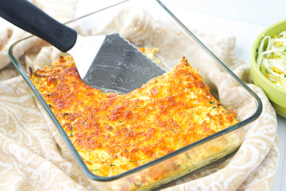 glass baking dish with keto cheesy casserole with a piece take out