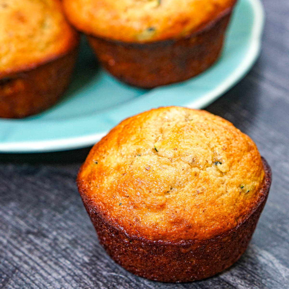 Closeup of a low carb zucchini protein muffin with a blue plate in the background.