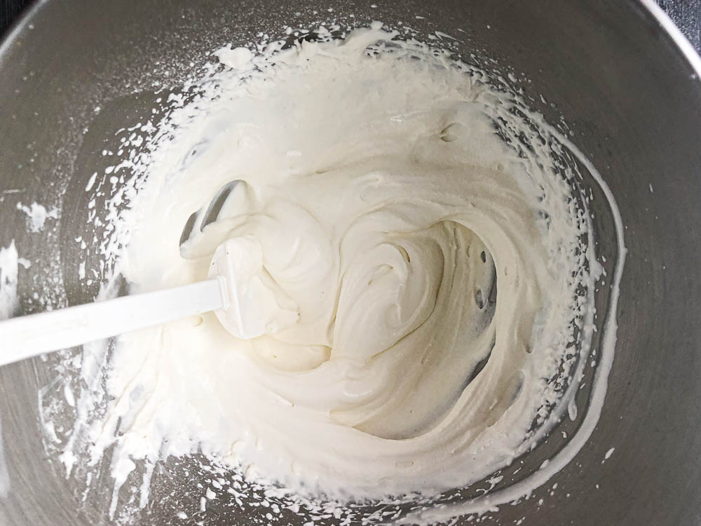 silver mixing bowl with whipped cream and spatula