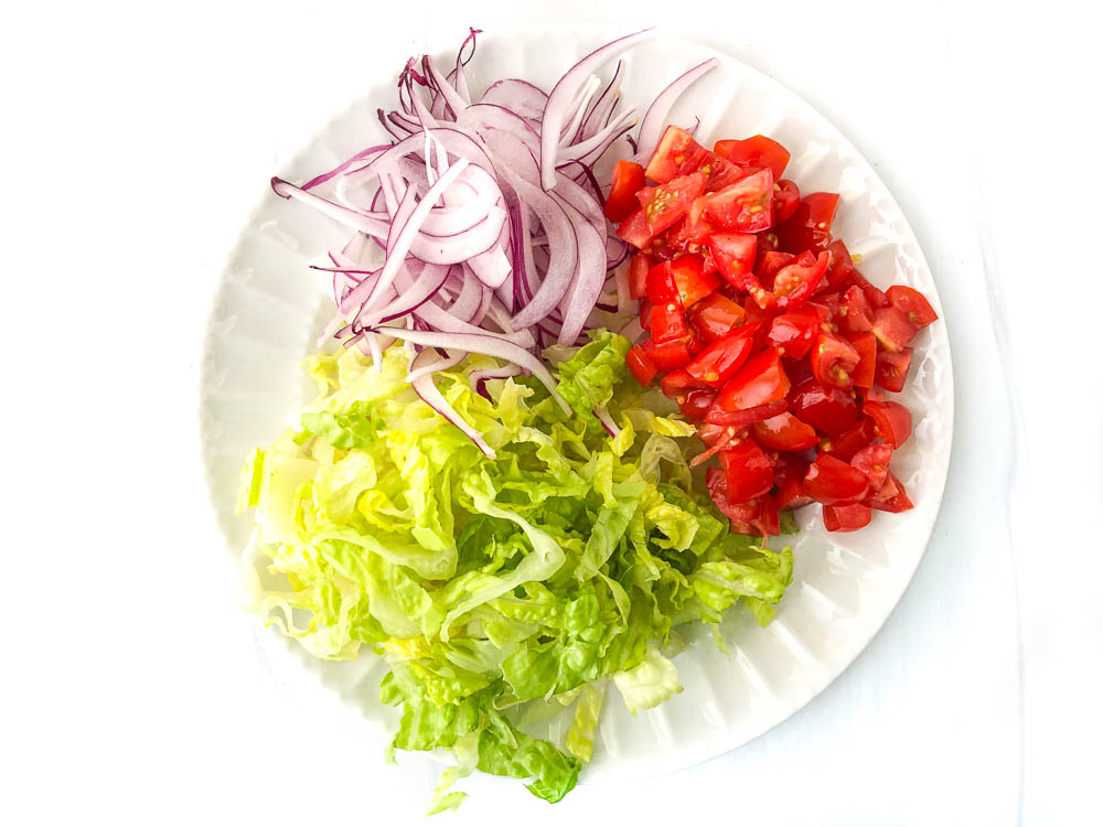 gyro toppings on white plate - red onions, romaine lettuce and fresh tomatoes 