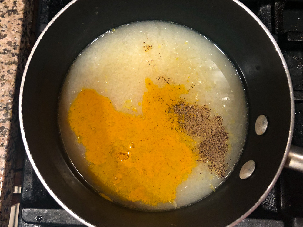 pan with rice, broth, turmeric and spices