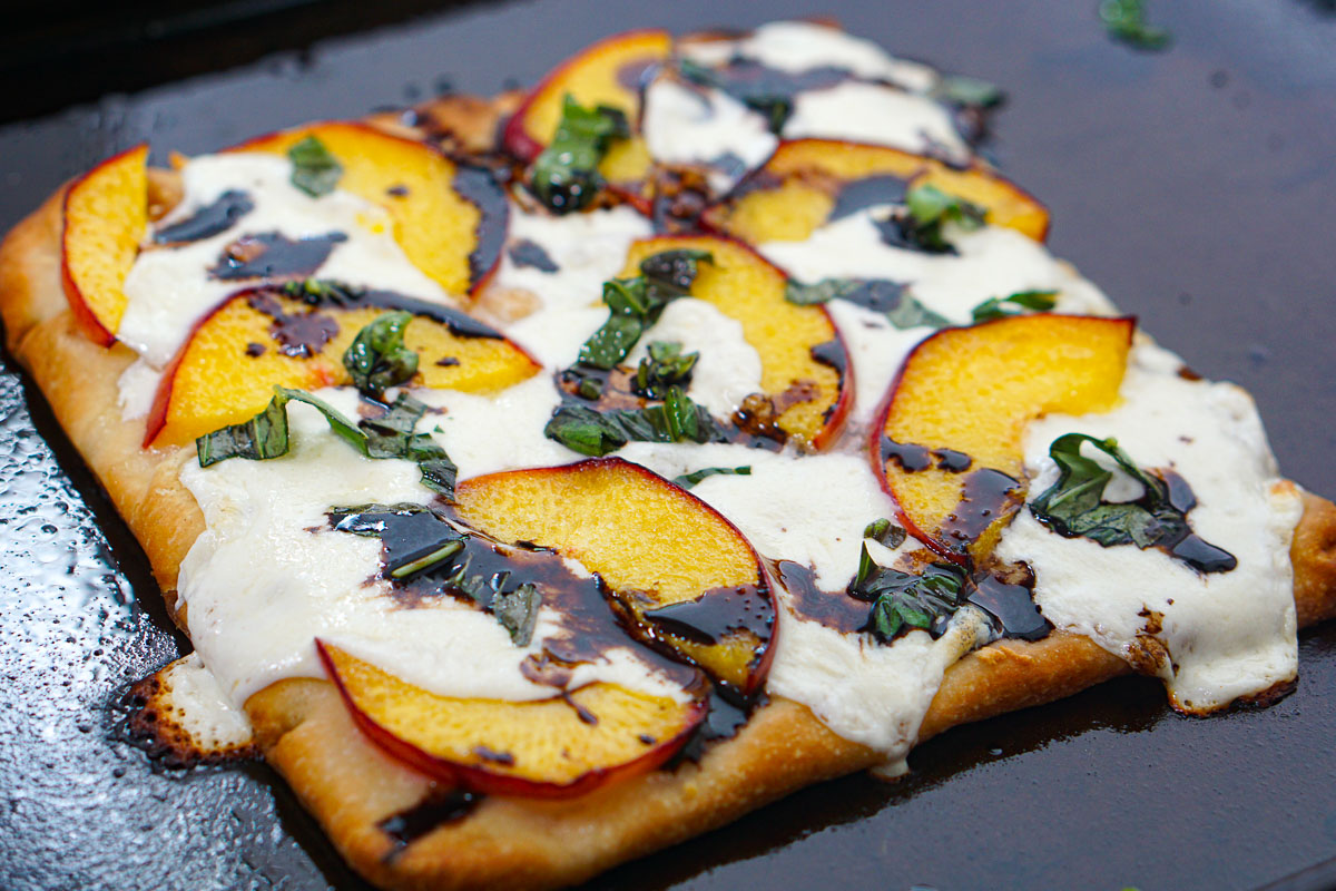 Closeup of half of Aldi flatbread used to make a peach, basil and mozzarella pizza.