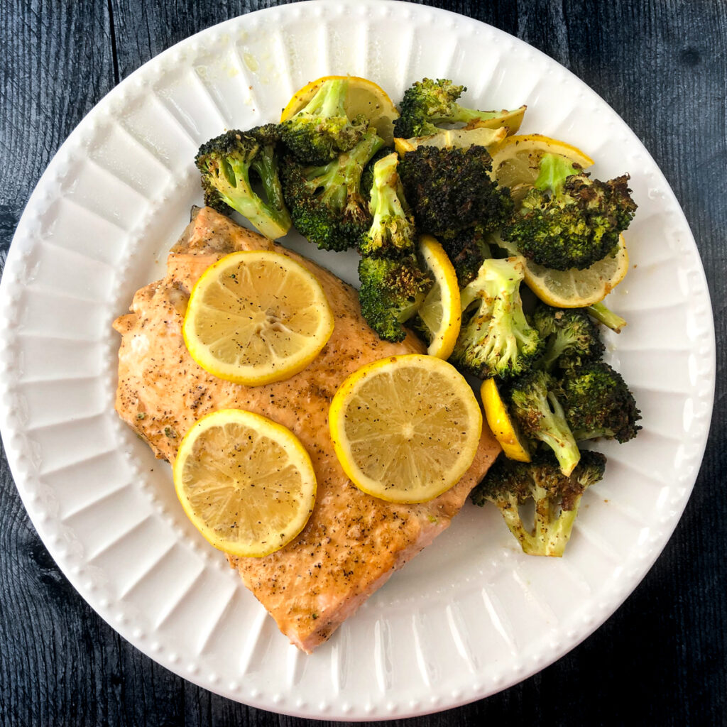 white plate with air fryer cooked salmon with roasted broccoli and lemon slices