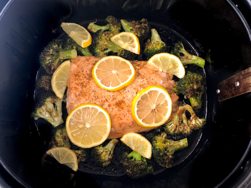 air fryer basket with cooked salmon and broccoli