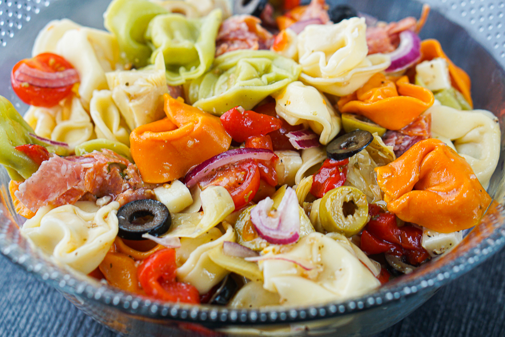 closeup of bowl of antipasto tortellini salad with olives, cheeses, meats and more