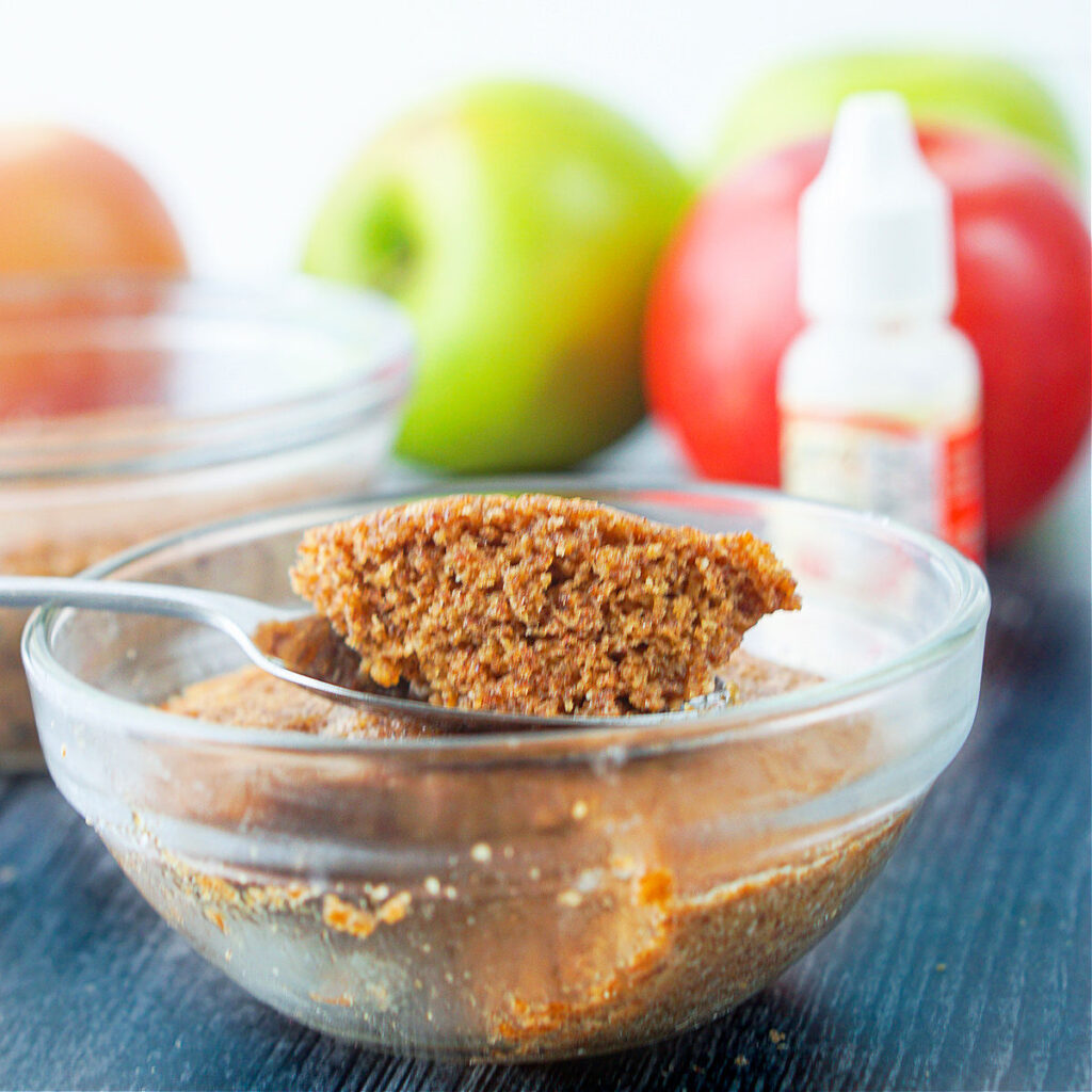 closeup of a spoonful of apple cinnamon microwave muffin with apples in the background