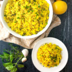 white bowl and plate with lemon herb rice and fresh herbs and lemons