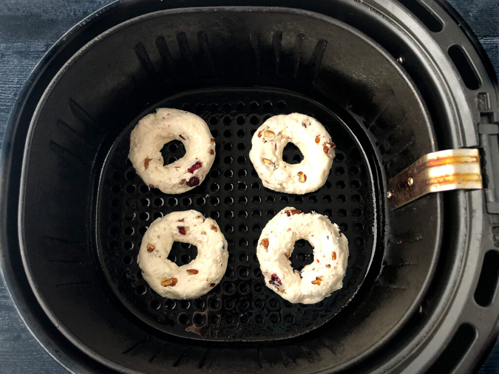 air fryer basket with 4 bagels ready to bake