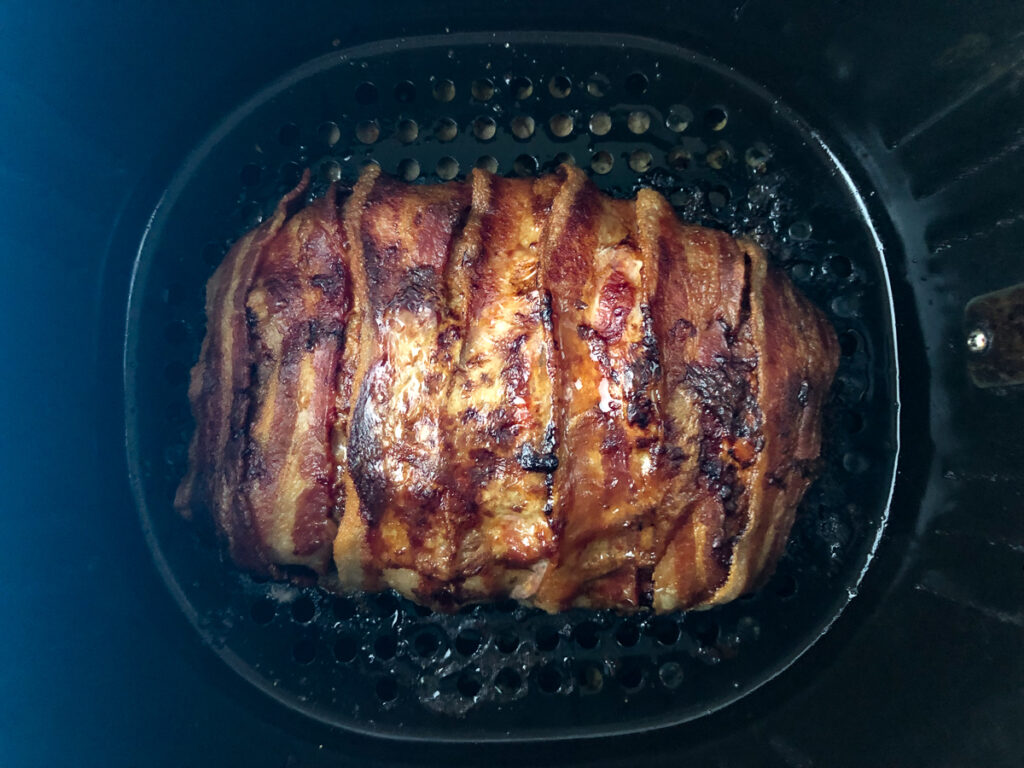 air fryer basket with cooked bacon wrapped meatloaf